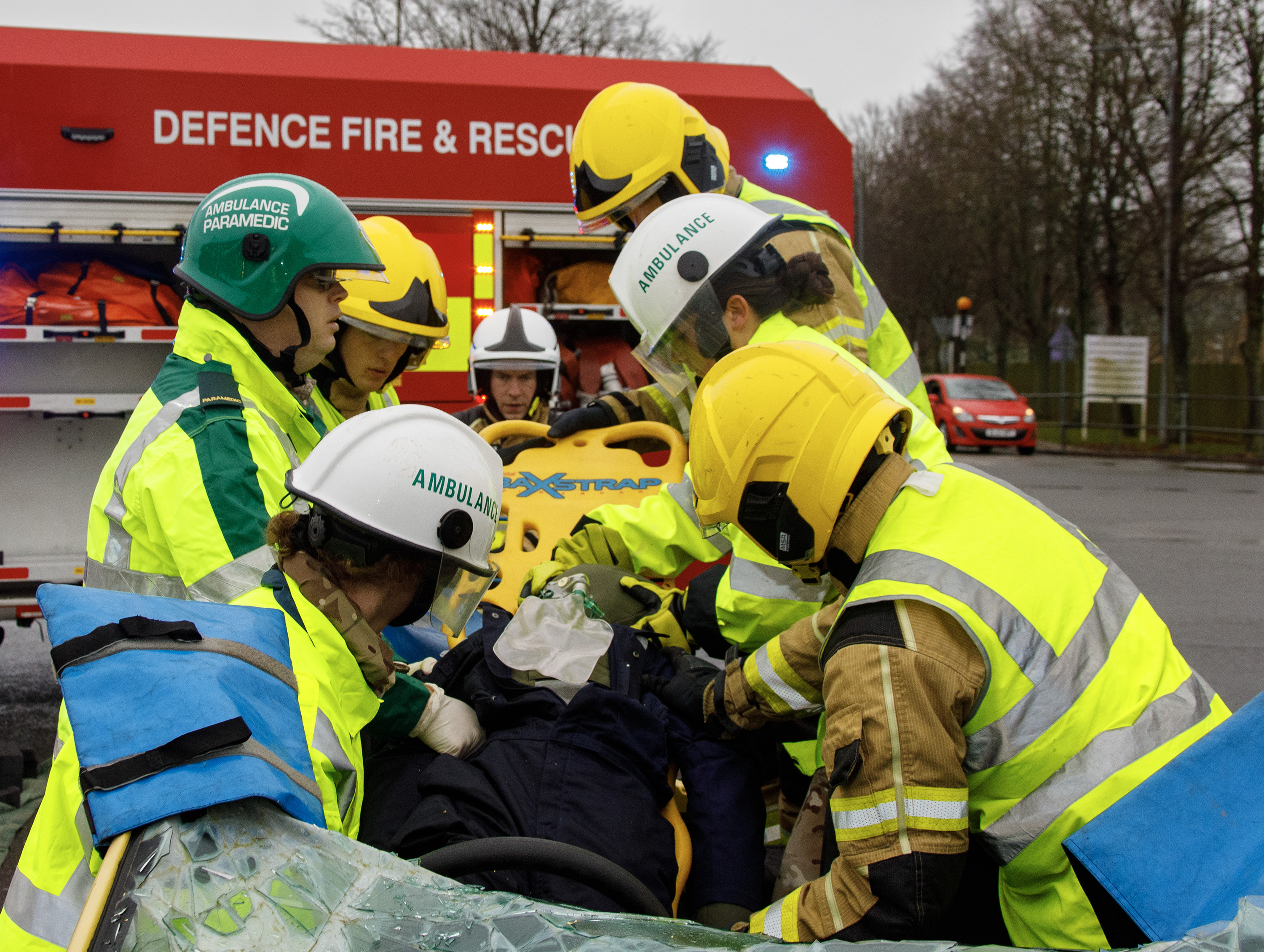 Photo - Image shows RAF medical and fire personnel with the injured driver, who had been extracted from the car via a roof removal, being placed on a long board prior to being placed onto a stretcher.